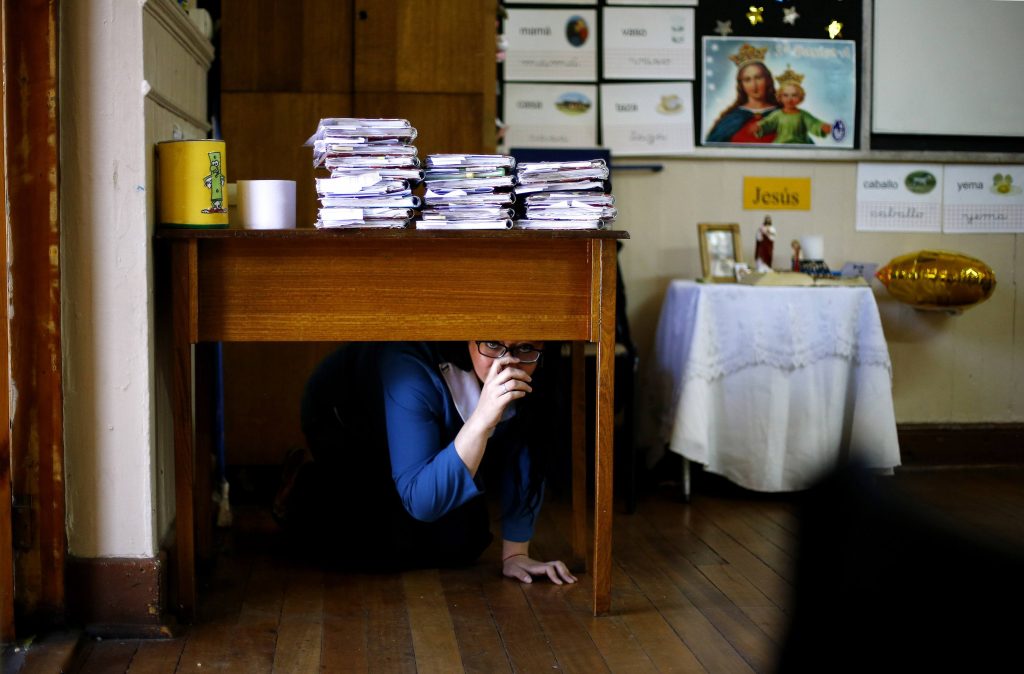 A Teacher Takes Cover Under Her Desk Inside A School During An